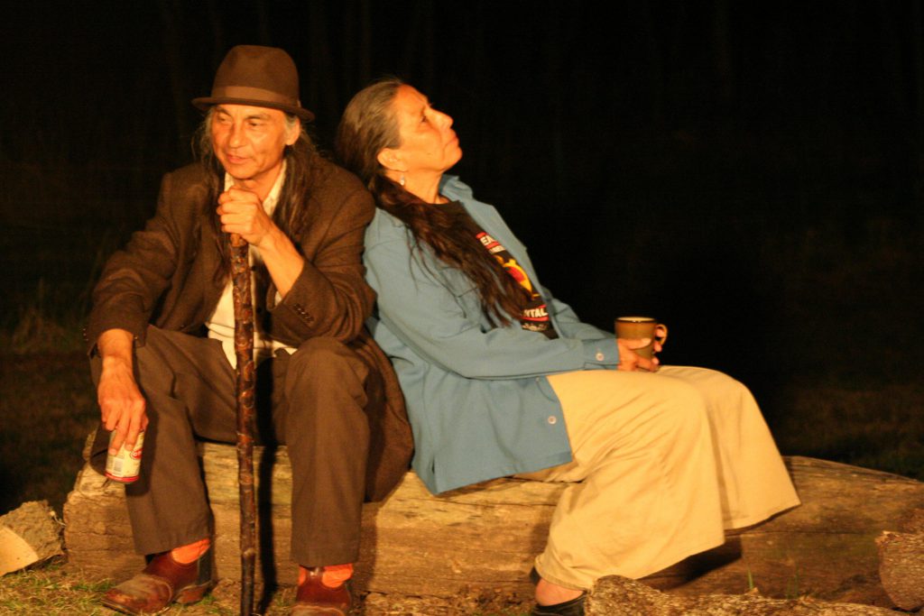 A still from "Barking Water" featuring the two leads leaning against each other while seated on a log