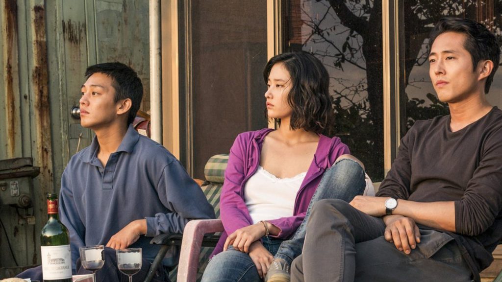 Still from "Burning" featuring the three main characters sitting on a porch and looking off into the distance