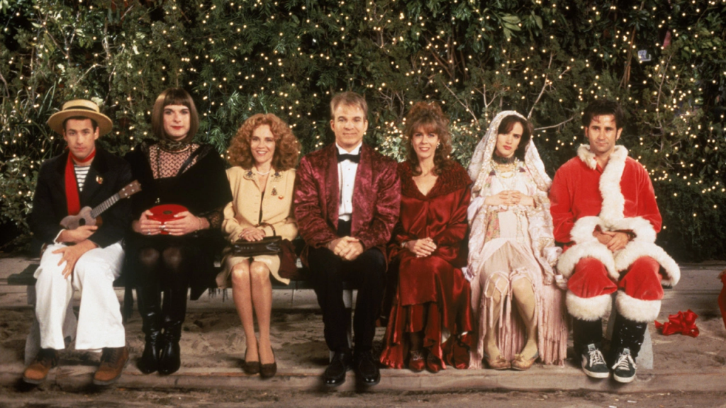 A still from "Mixed Nuts" featuring the main cast dressed up for Christmas sitting on a park bench