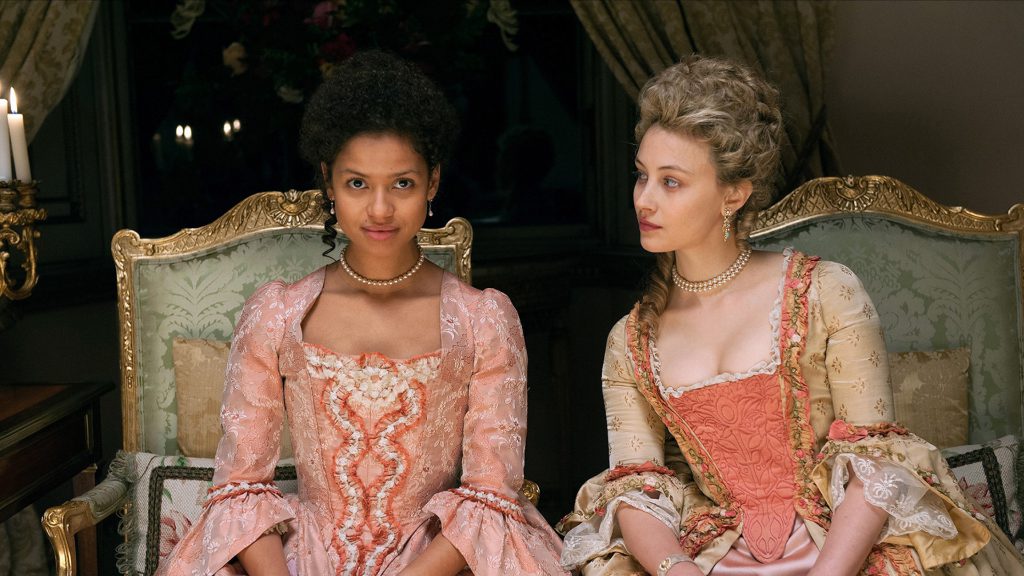 Still from "Belle" featuring a mixed race woman in period clothing looking towards the camera while a white woman leans into her