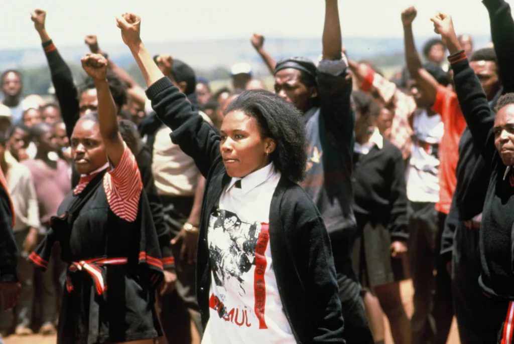 Still from "Sarafina!" featuring a crowd of students raising their fists in the air