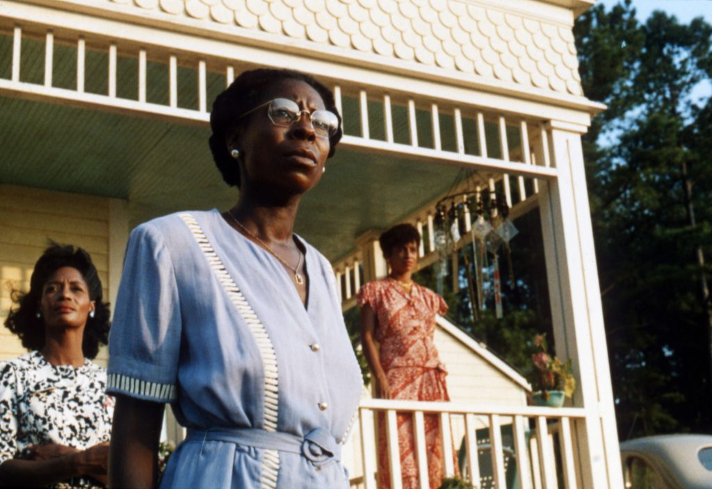 Still from "The Color Purple" featuring three women standing out front of a house