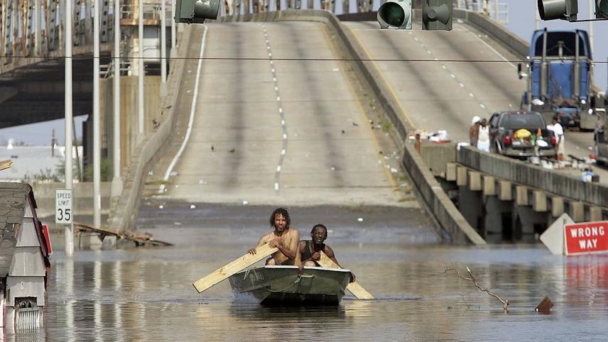Still from "When the Levees Broke" featuring two men rowing a boat through a flooded highway