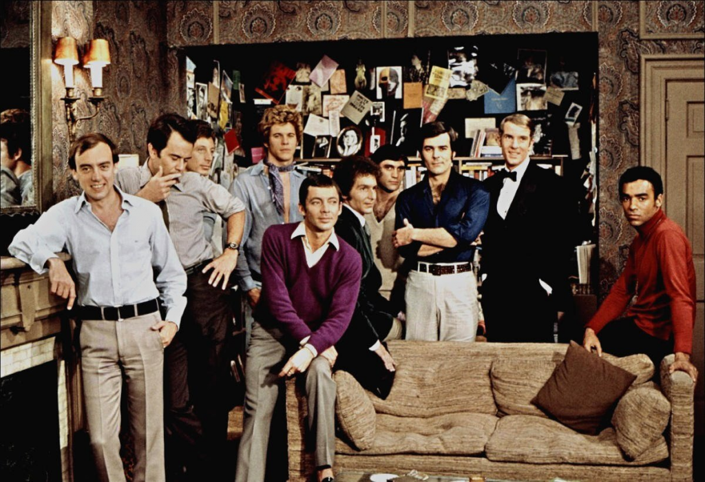 Still from "The Boys in the Band" featuring a large group of men standing around a parlor