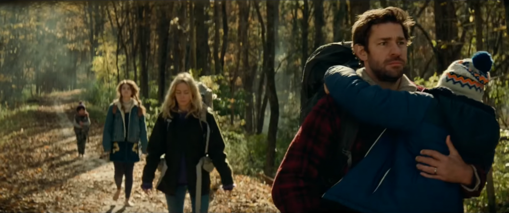 Still from "A Quiet Place" featuring a family hiking through the woods