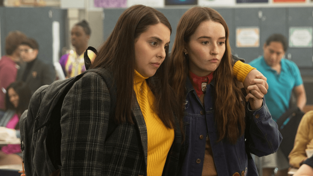 Still from "Booksmart" featuring two teen girls standing in a classroom with their arms around each other