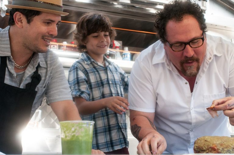 Still from "Chef" featuring two adults and a kid smiling while making a sandwich