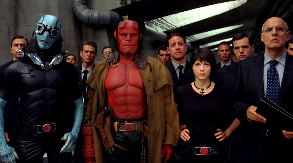 Still from "Hellboy" featuring a large crowd of characters standing in a large hallway
