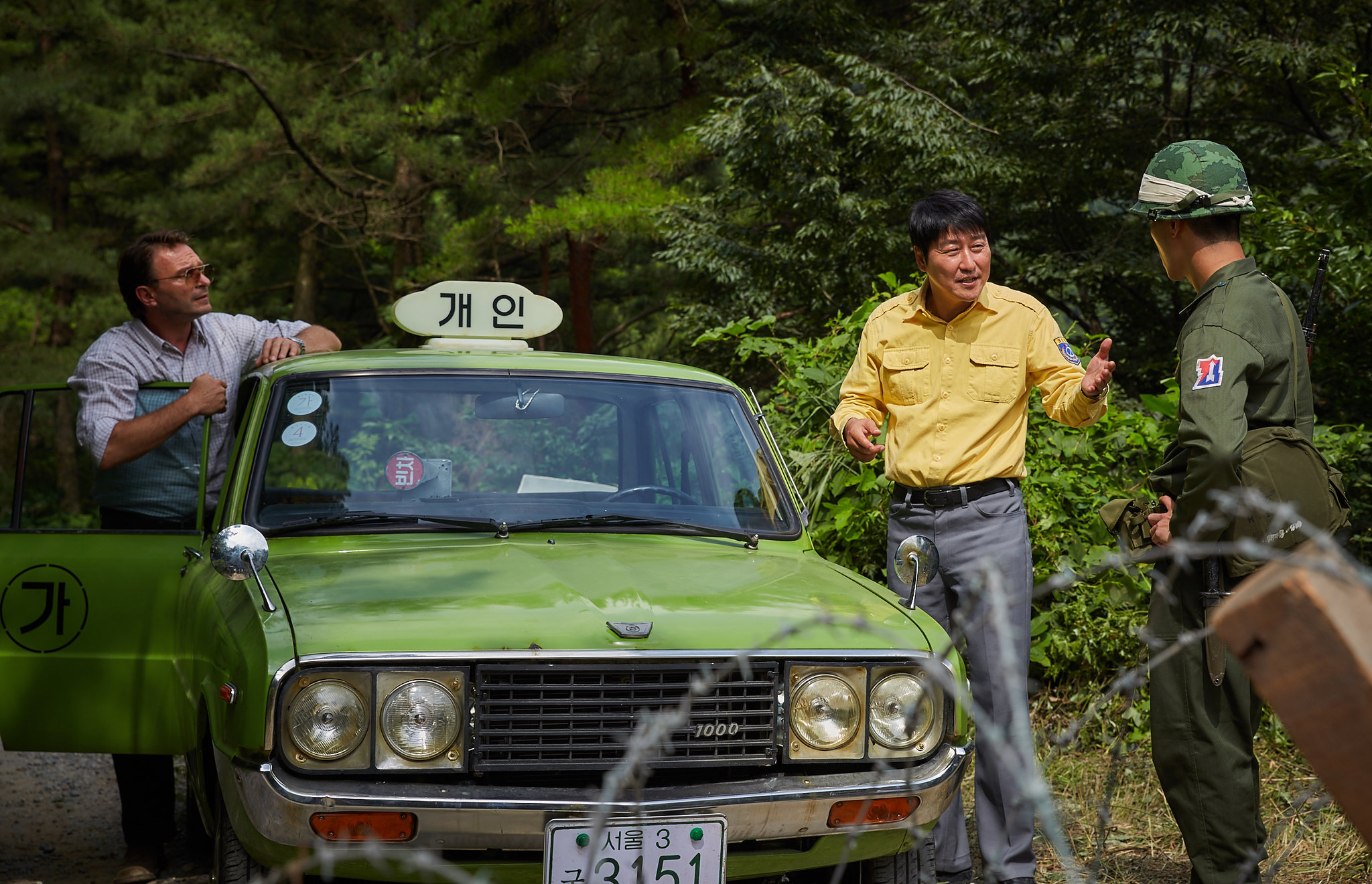 Still from "A Taxi Driver" featuring a South Korean taxi driver and a German journalist speaking to a South Korean soldier