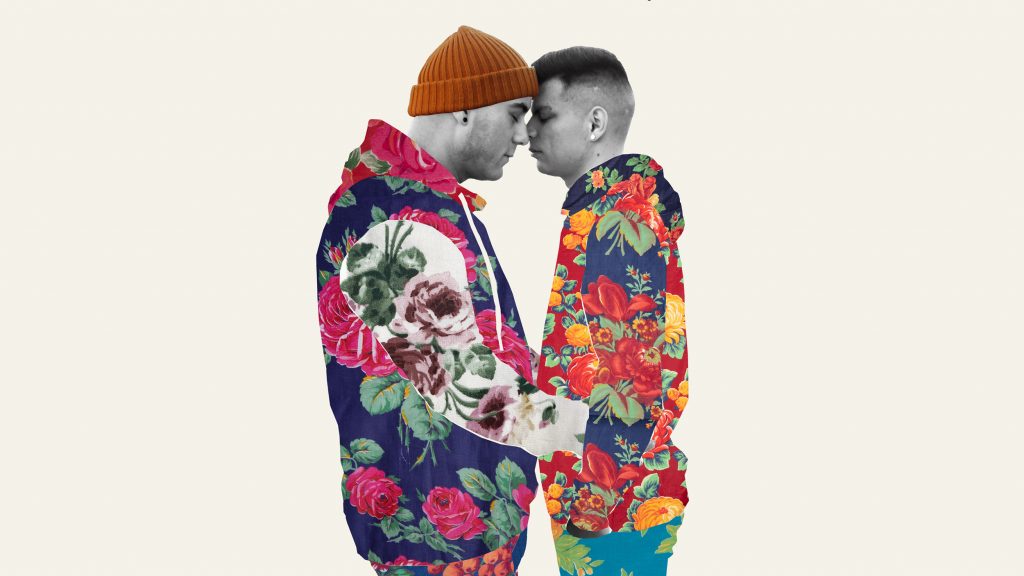 A young gay couple in brightly patterned clothing touching their heads together