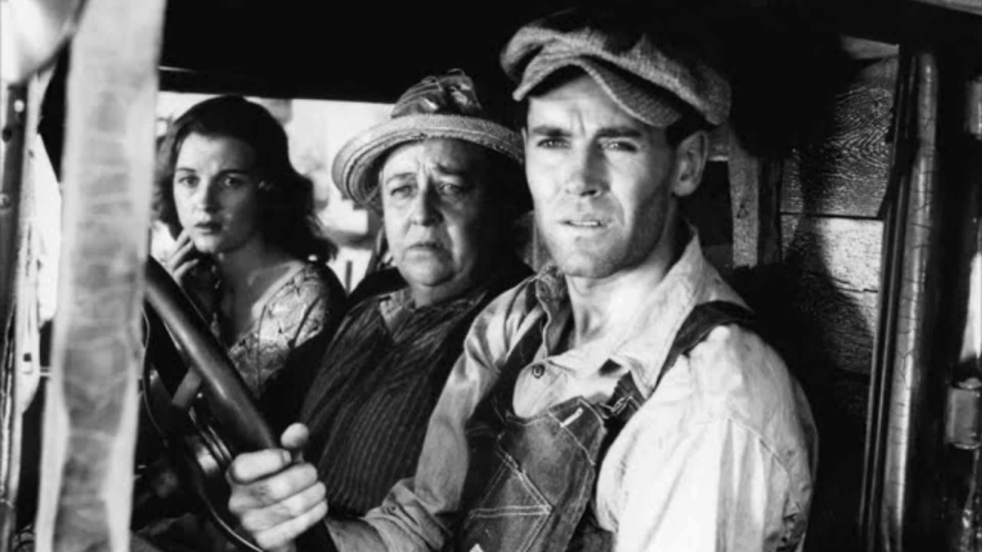 Three people sit in the front of a vehicle.