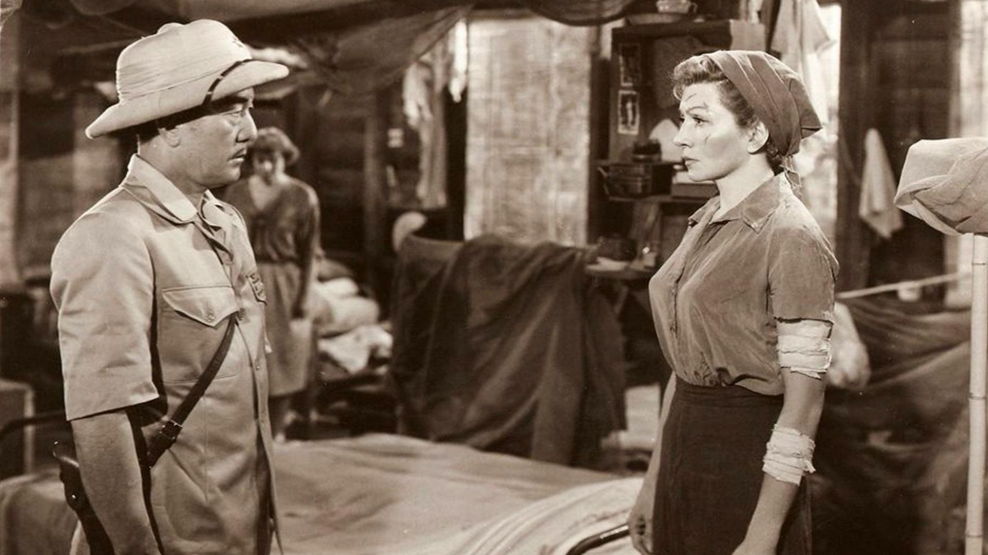 A soldier speaks to a woman in what looks to be a makeshift hospital.