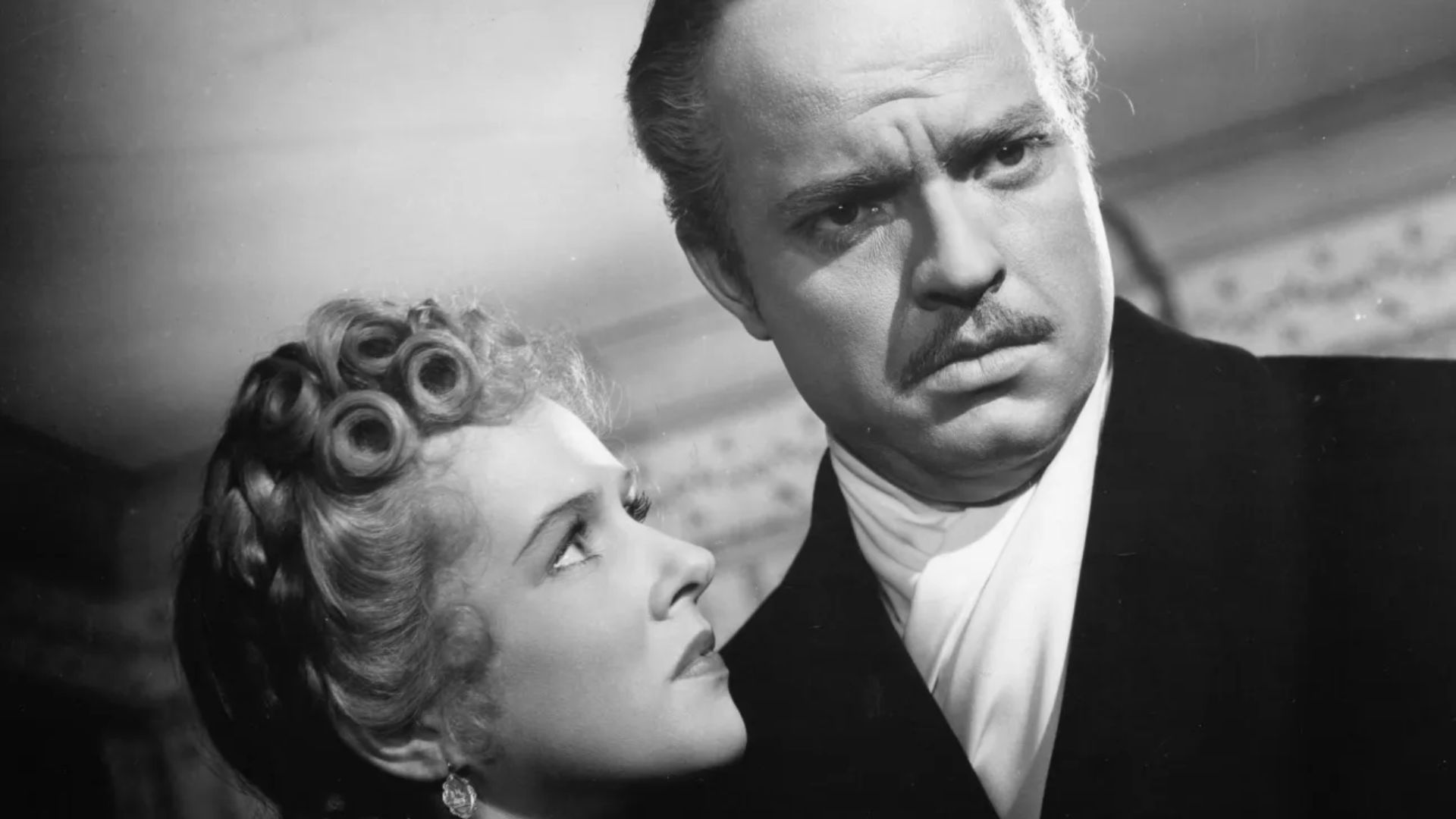 A woman looks up at a man in formal dress.