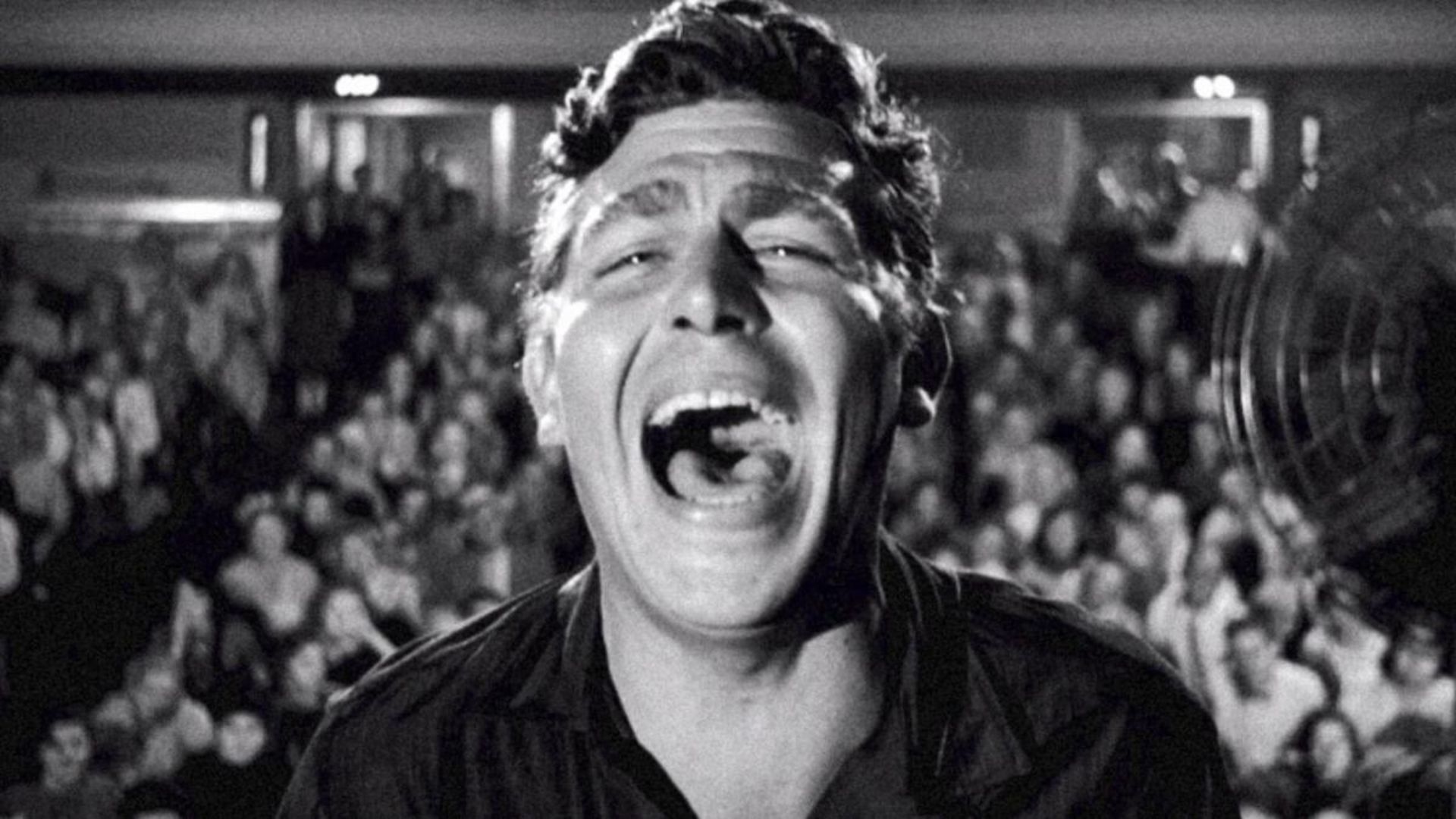 A man is shown shouting with a crowd in the background.