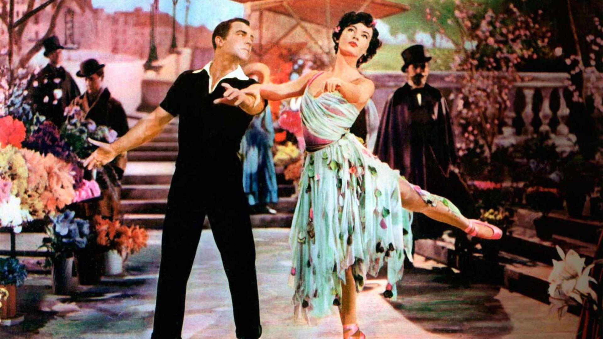 A man and a woman dance against a colorful background.