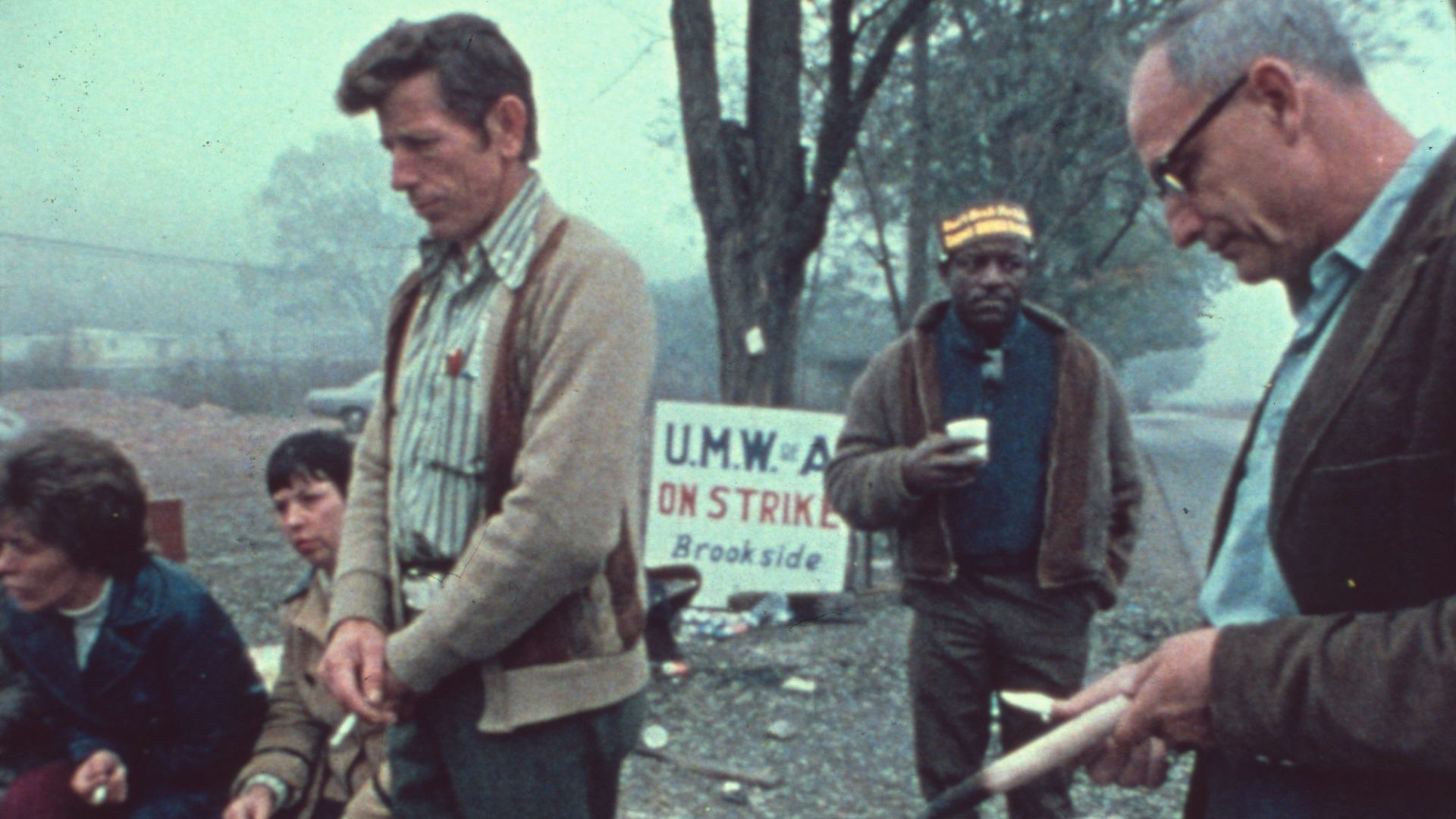 Striking workers stand near a "UMWA ON STRIKE, BROOKSIDE" sign.