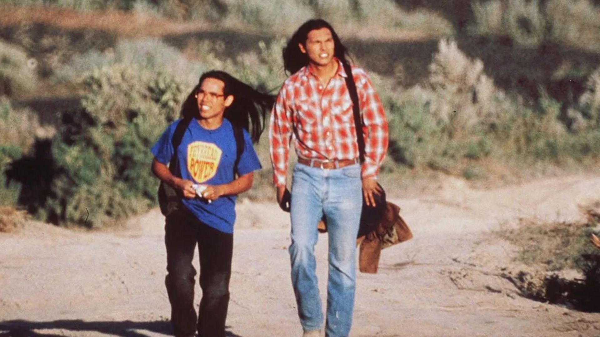 Two men walking through a desert.