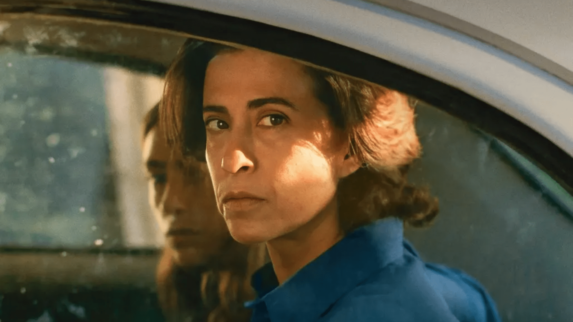 A middle-aged woman stares out of the window of a car.