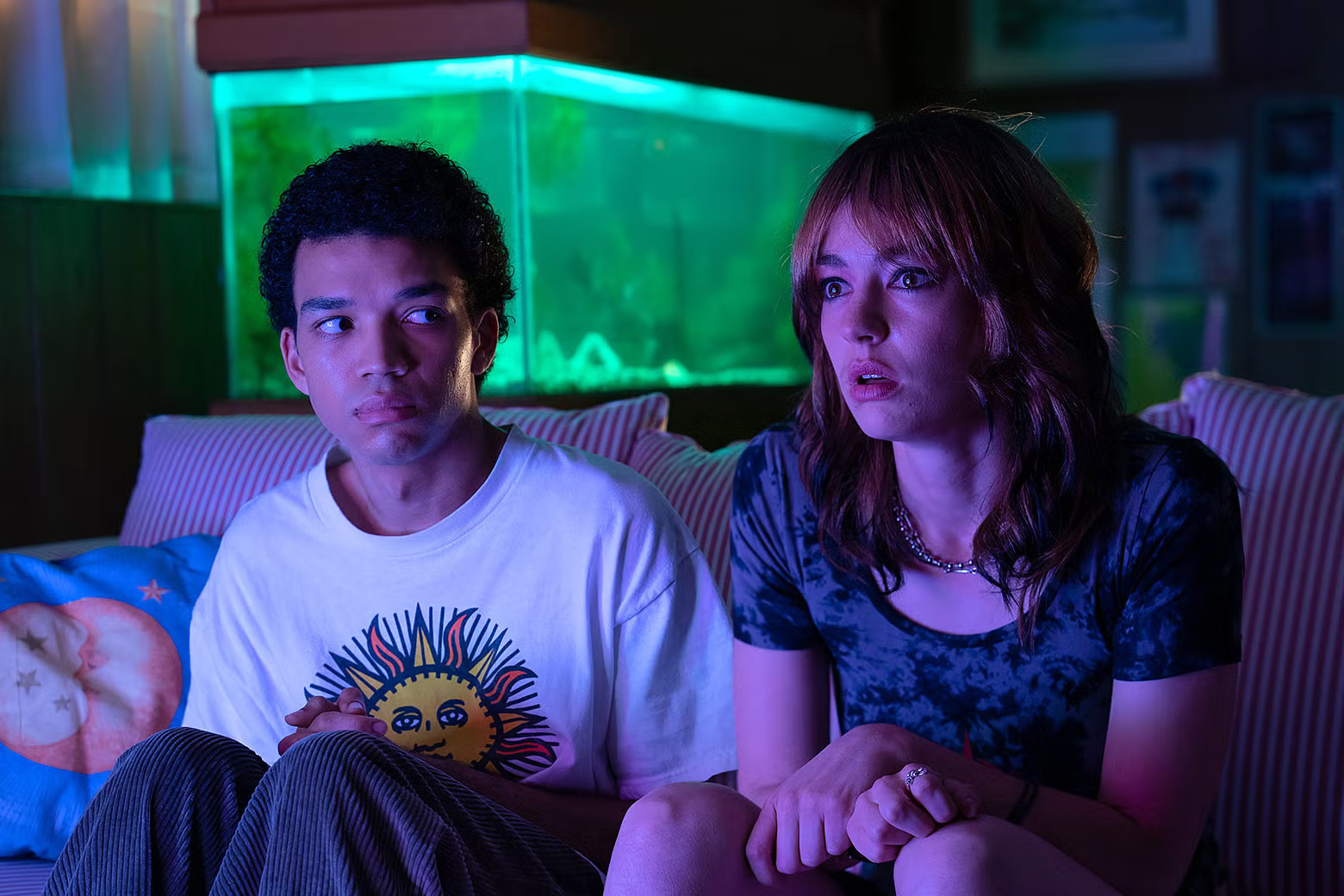 Teenager looking sideways at another teen engrossed in TV