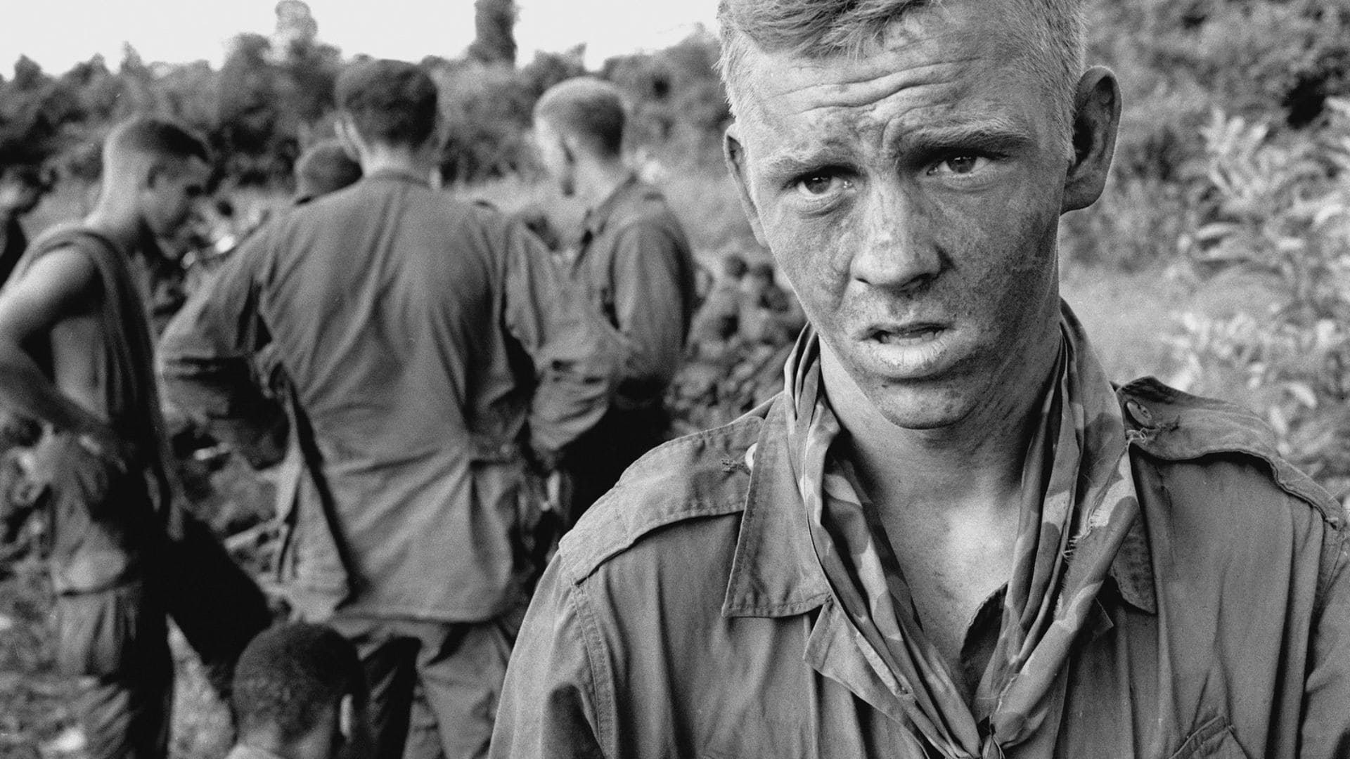 A young man has his mouth agape, his face is dirty as he looks towards the camera.