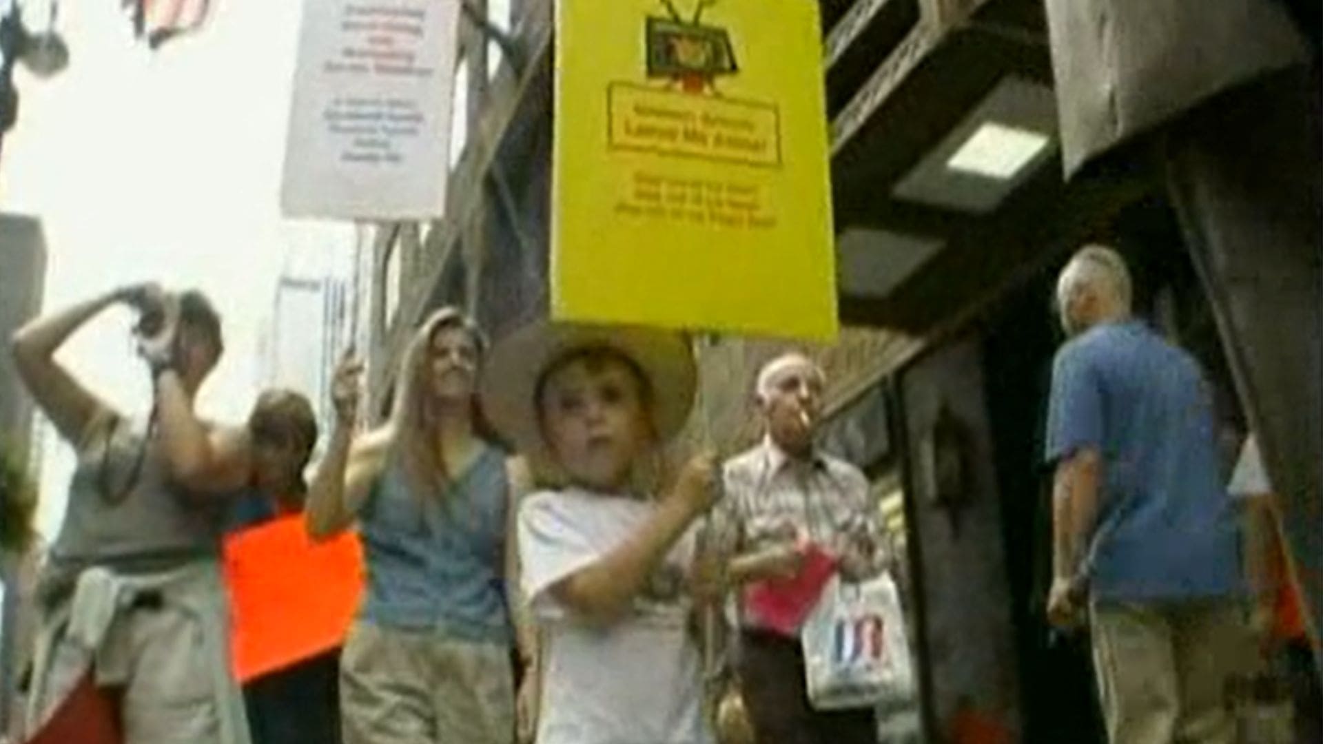A young boy pickets with a sign in front of a crowd of protestors.