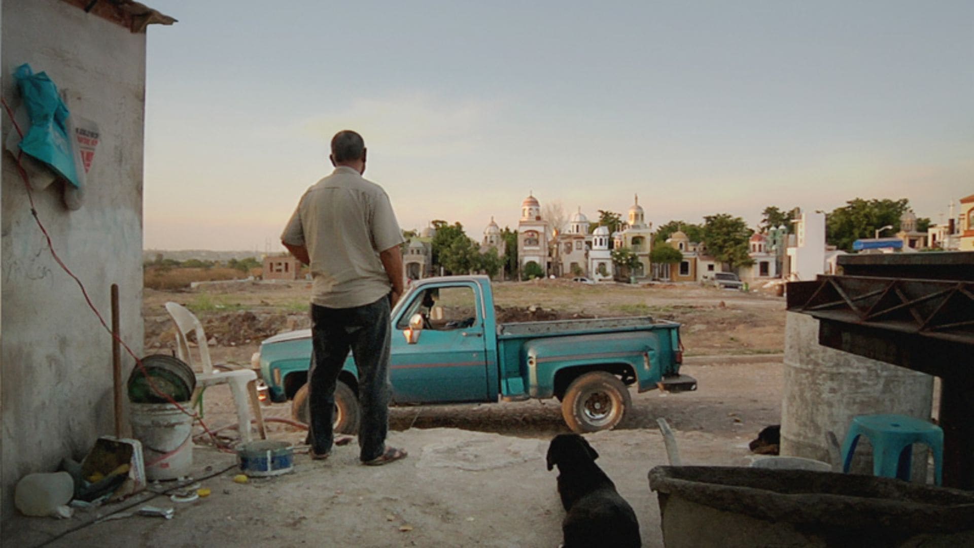 A man stands on a platform in front of a blue truck.