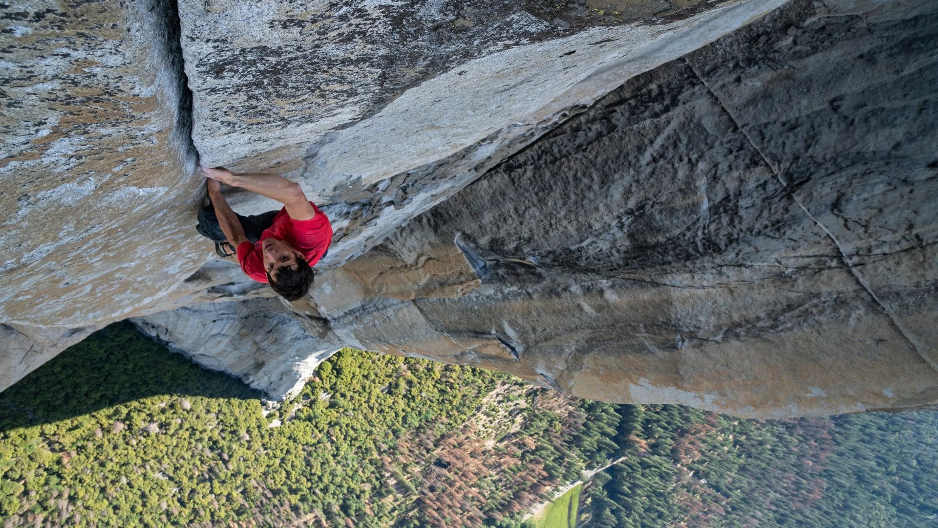 A man climbs a vertical formation without a harness.