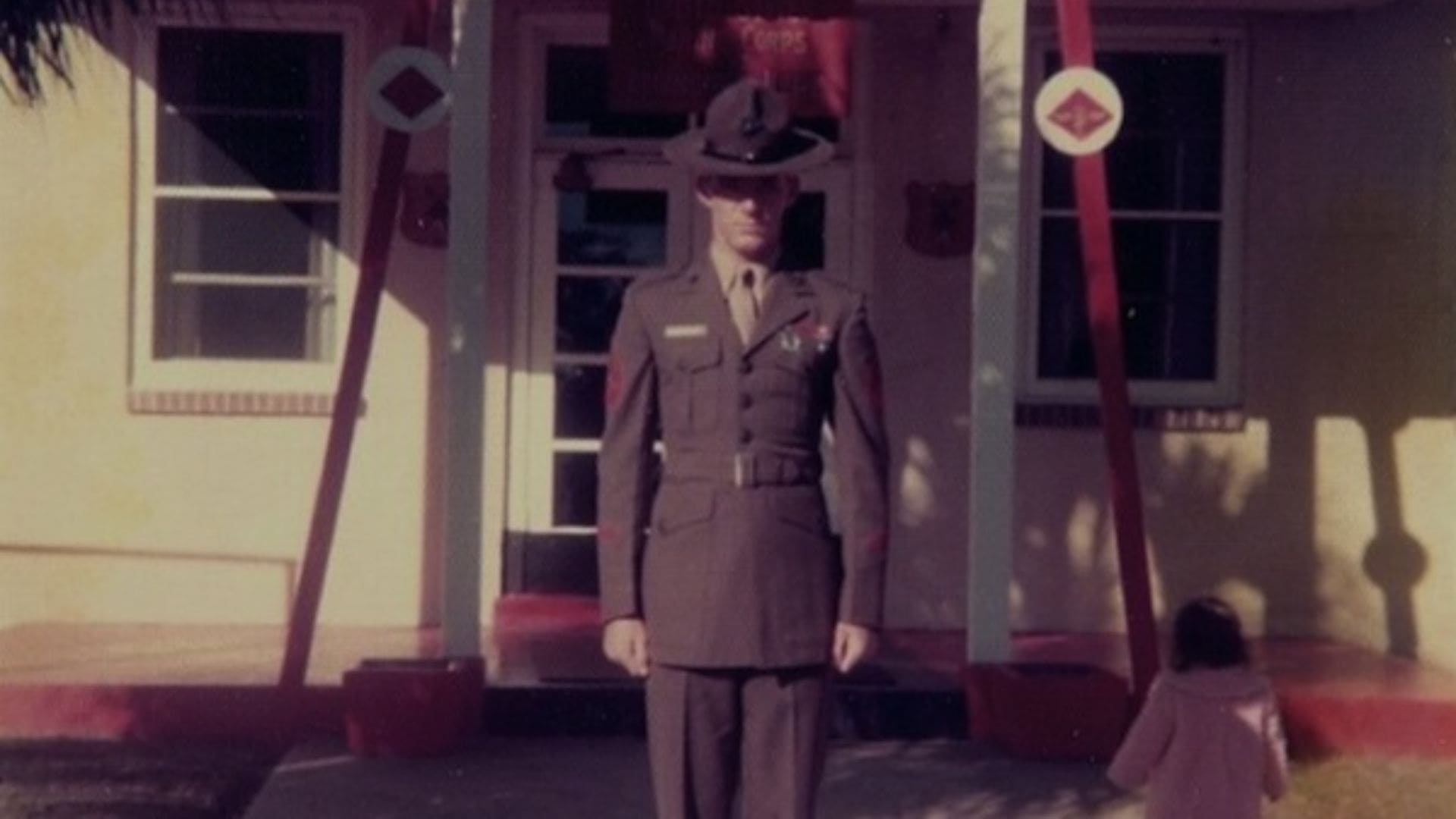 A soldier stands straight in front of a door.