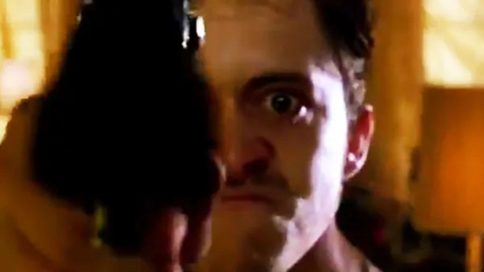 A man holds a gun so close to the camera that it covers half his face.