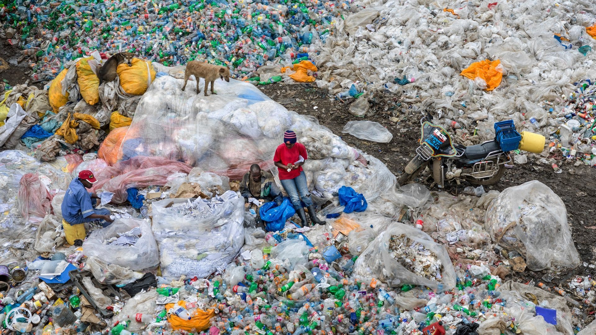 Two people stand in an enormous landfill.