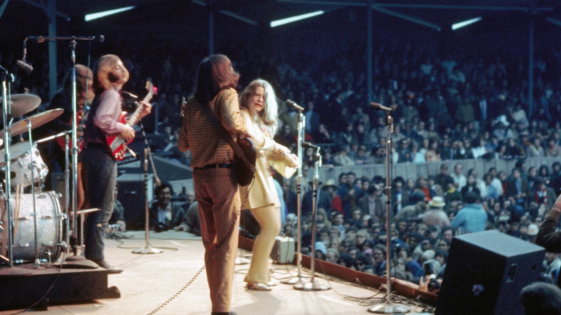 Janis Joplin performs with her band in front of a packed stadium.