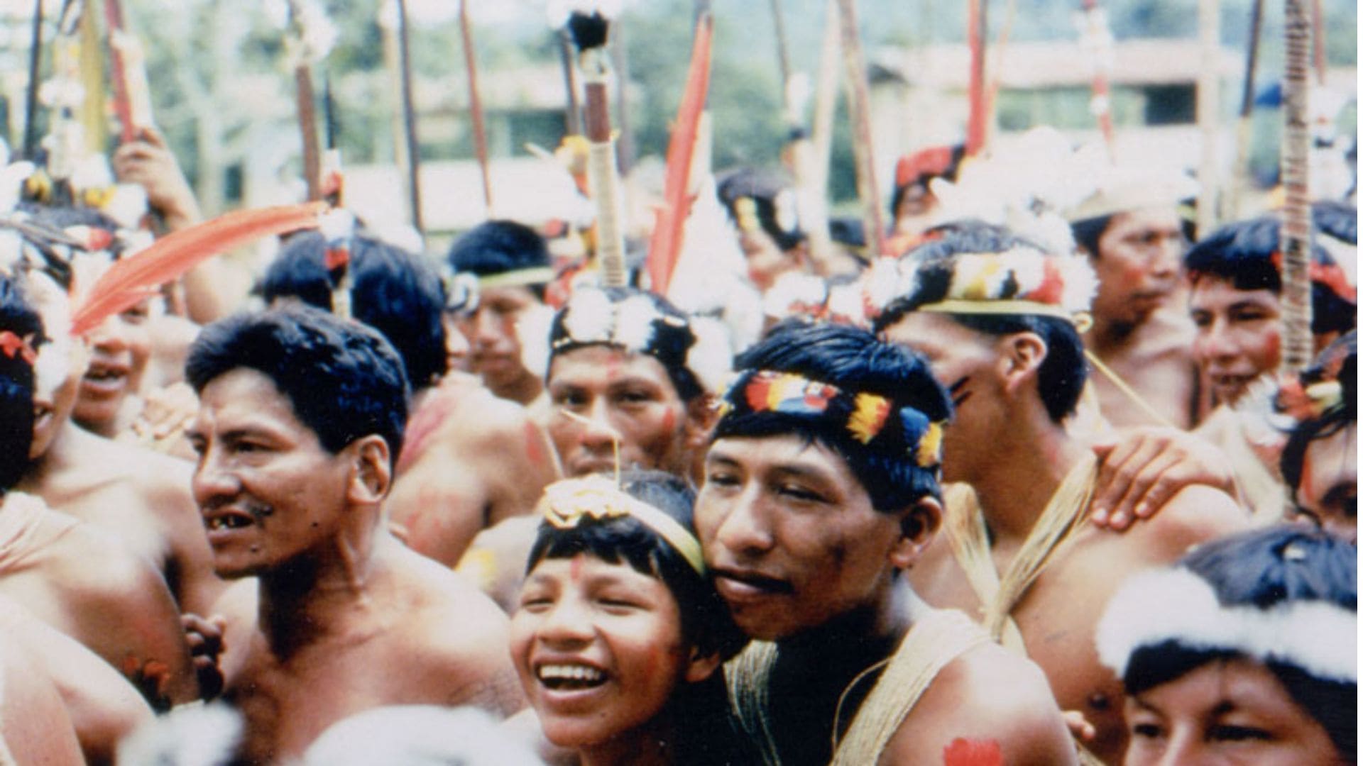 A small crowd gathers close to each other, most wearing bead and feather head ornaments.