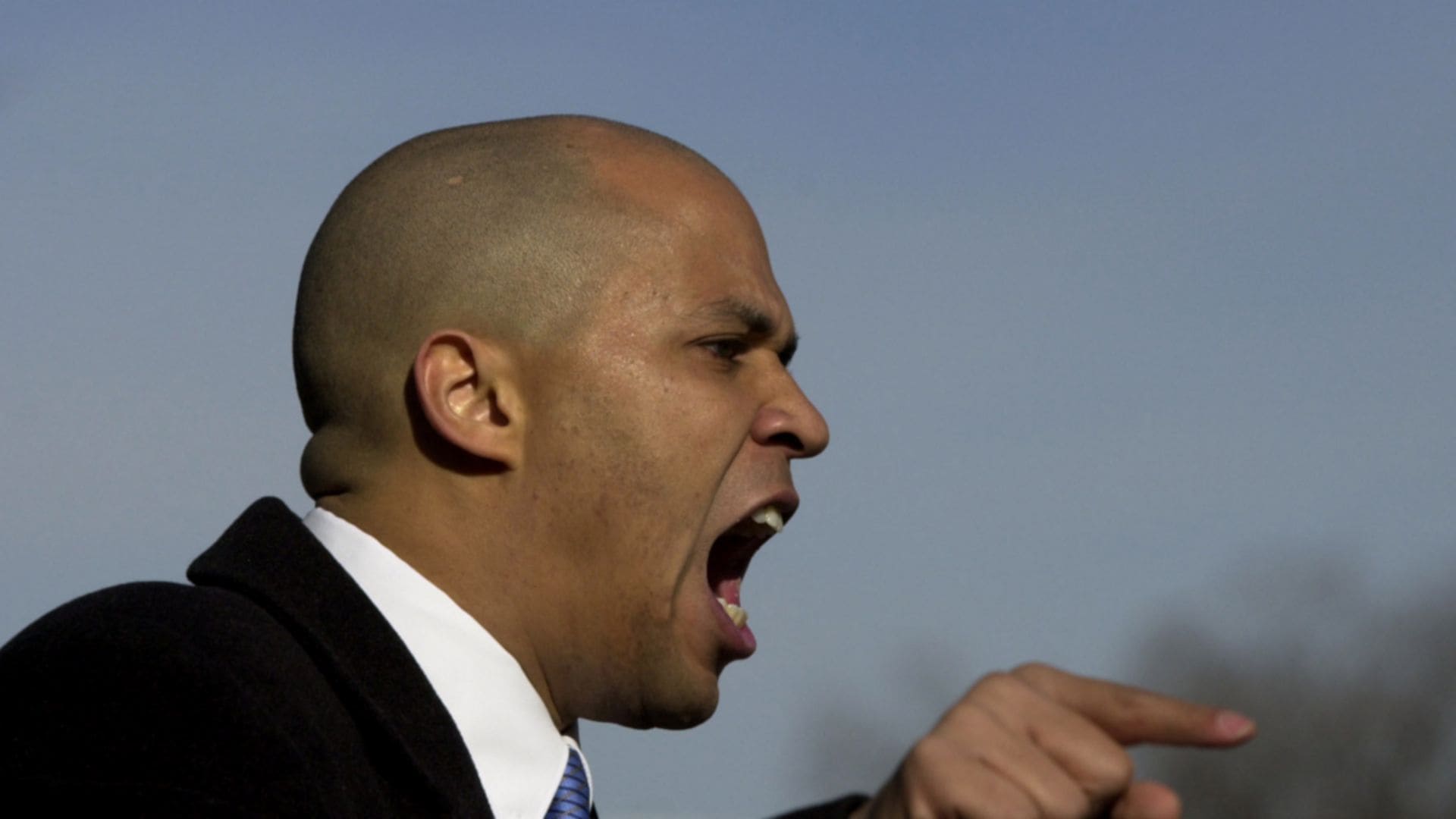 A side profile angle of politician Cory booker pointing and yelling.