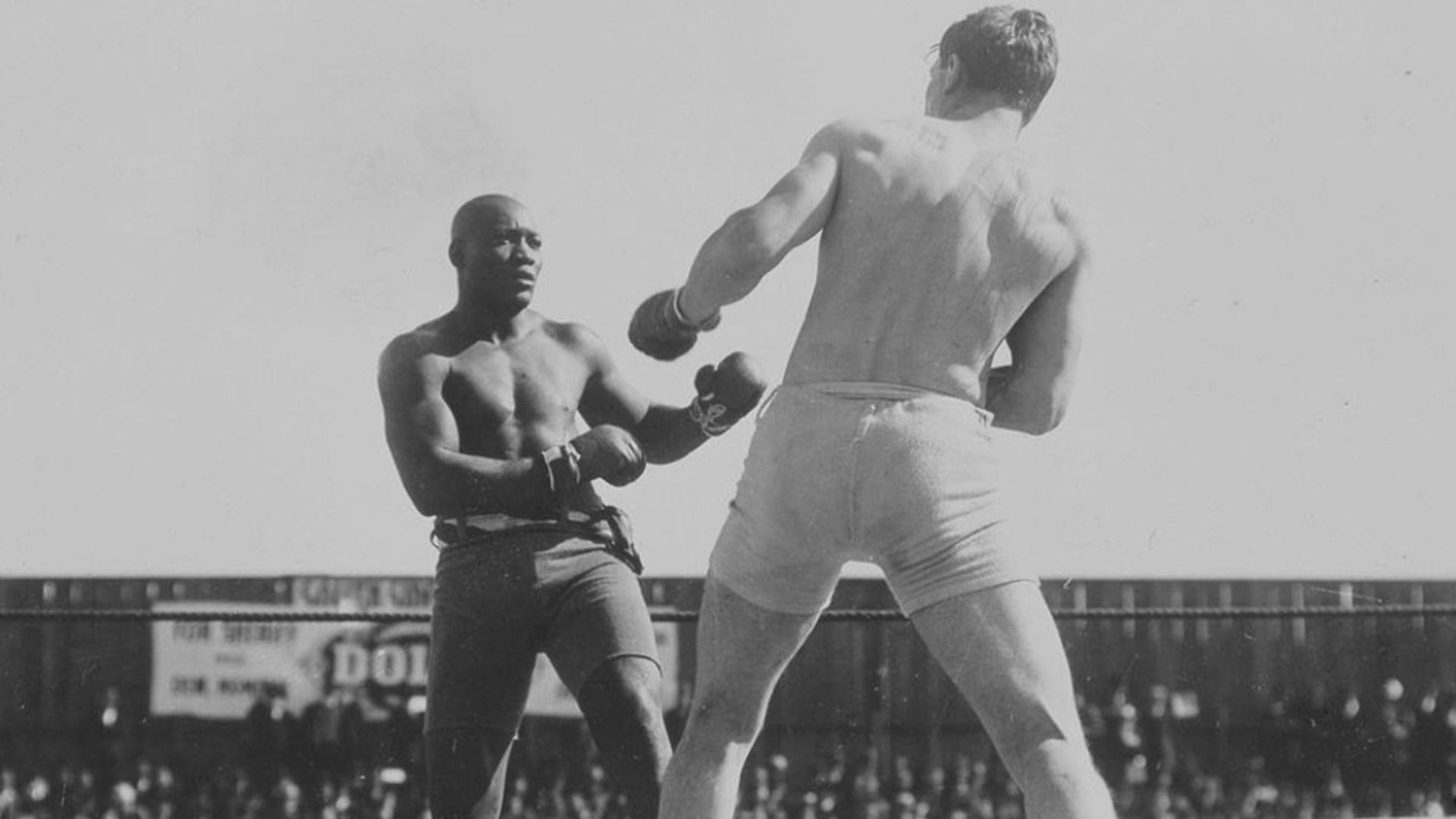 Two men are boxing in front of a crowd of people.