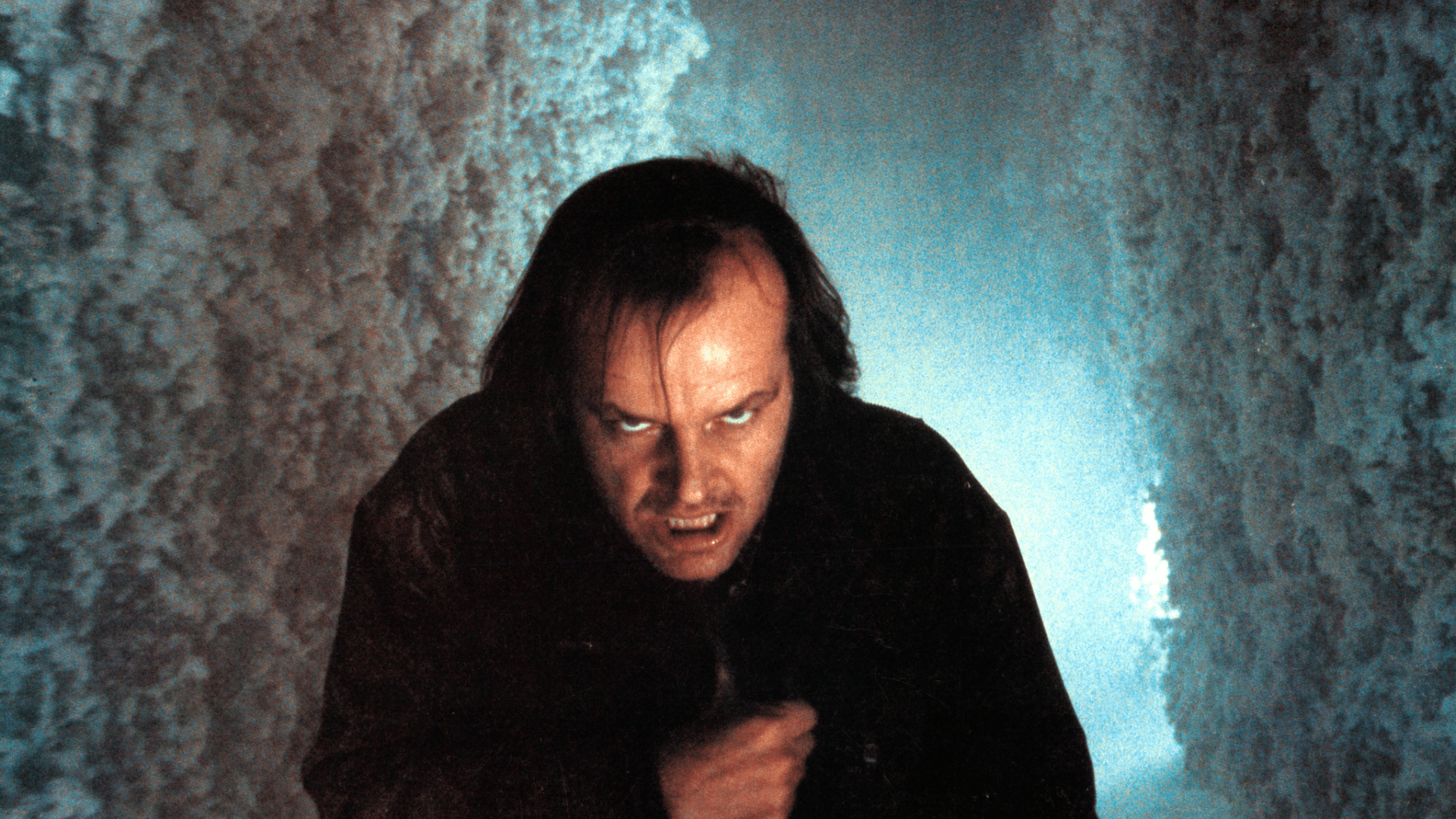 A man crouching in snow surroundings looks threateningly up towards the direction of the viewer.