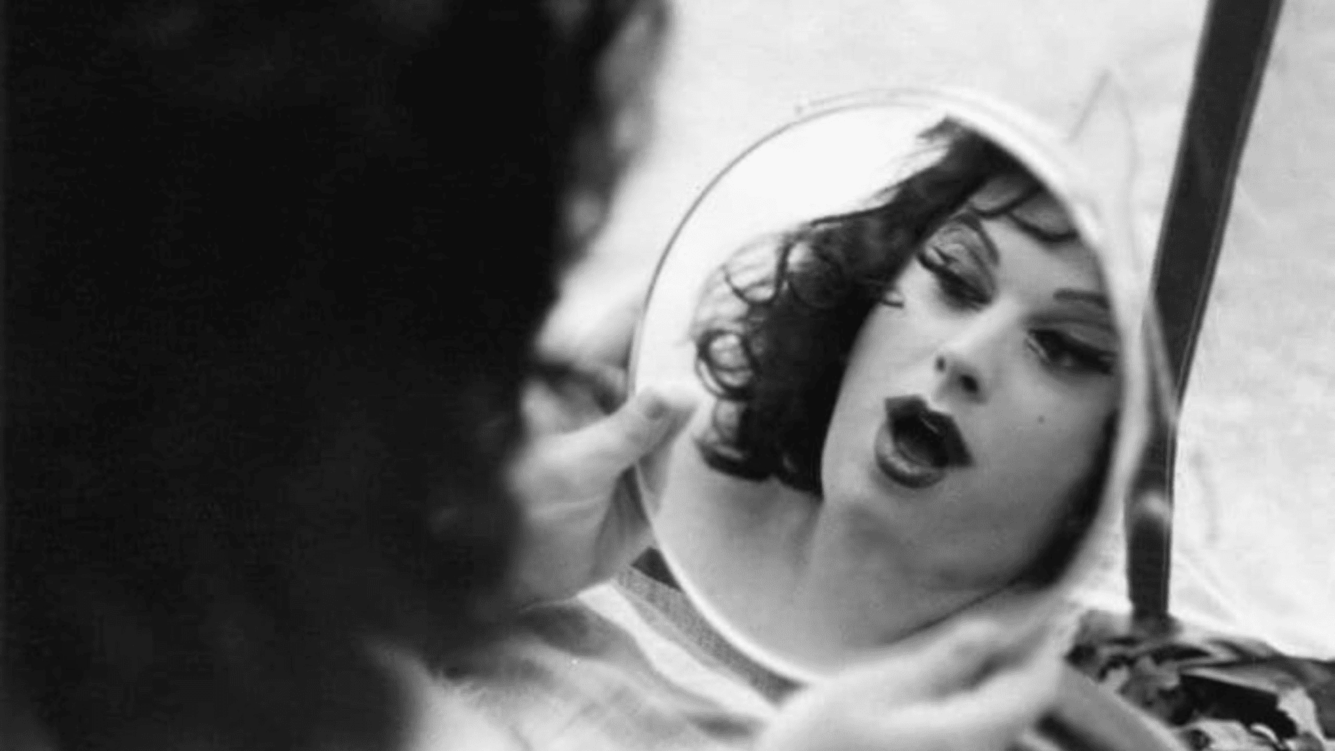 A woman stares at her reflection in the mirror.