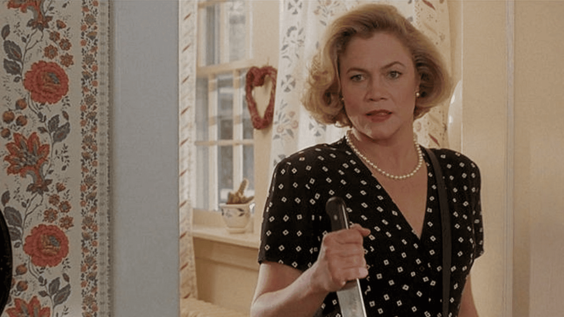 A middle-aged woman holds a knife.